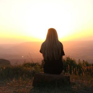 teen sitting and watching sunset or sunrise