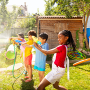 kids playing in water hose during summer break stock image