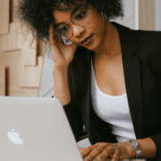 professional woman looking stressed in front of apple laptop