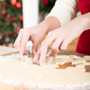hands cutting out holiday cookies with cookie cutter