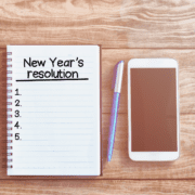 New Year's Resolutions list on notebook next to pen and cell phone