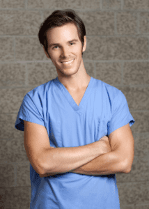 man in scrubs smiling with arms crossed