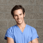 man in scrubs smiling with arms crossed featured image size