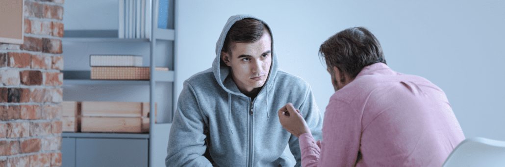 counseler talking to man in hoodie