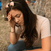 woman with dark hair and sunglasses looking anxious