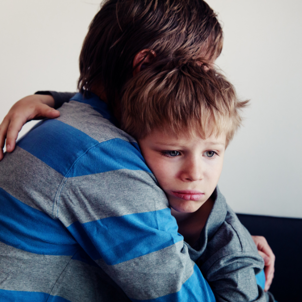 young boy being comforted, looking sad
