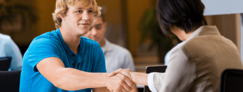 young blonde man shaking hand of HR professional stock photo