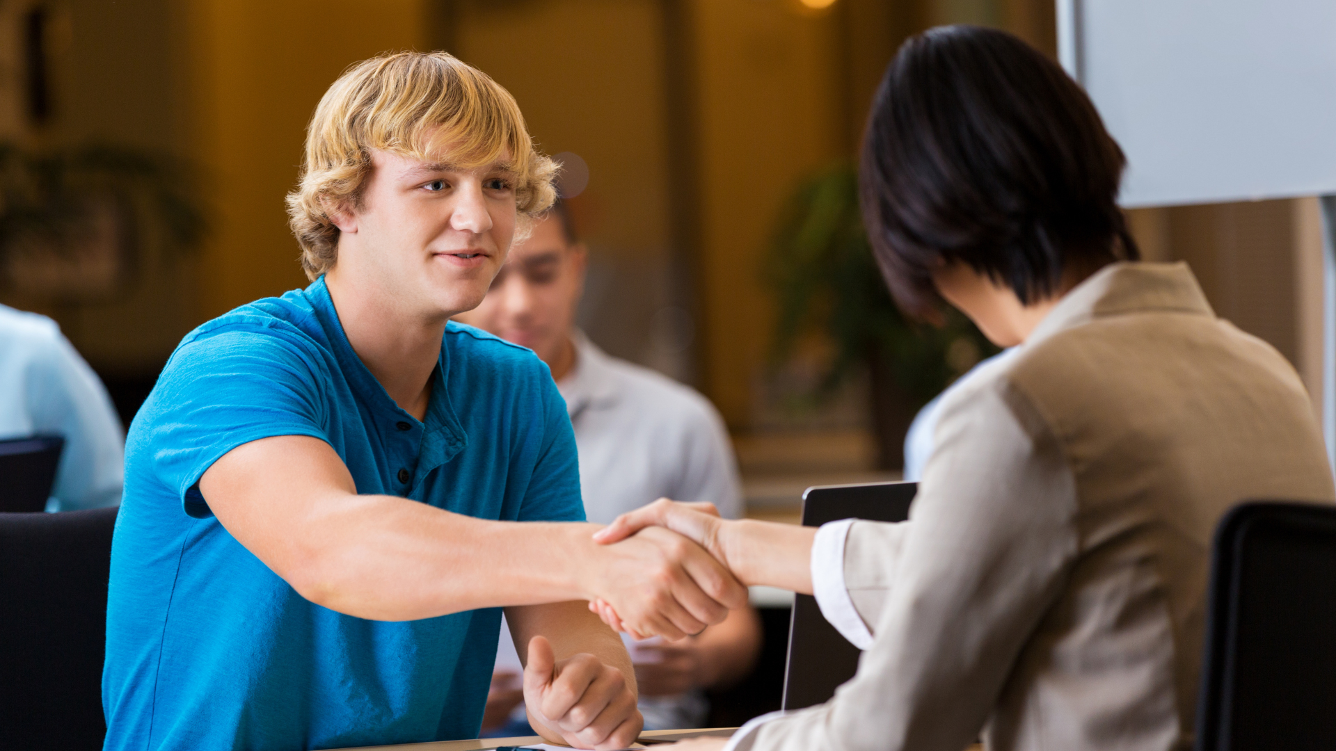 young blonde man shaking hand of HR professional stock photo