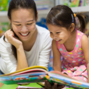 mom and daughter reading book together with smiles on faces