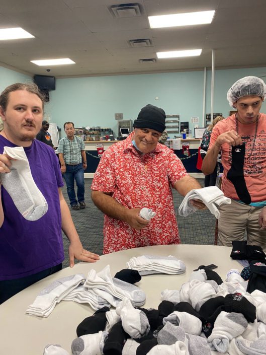 Three men holding up pairs of socks from Hanes
